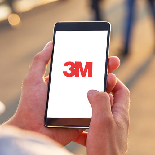 Hands holding mobile device with 3M logo on screen