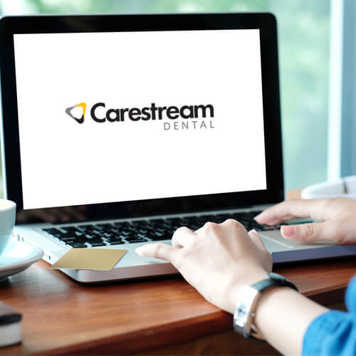 Female dentist's hands on a laptop with Carestream dental logo screen